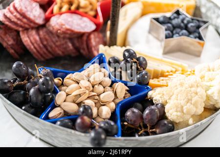 Le 4 juillet, un plateau de charcuterie est servi sur un support métallique à deux niveaux rempli de fromage, de craquelins, de salami et de fruits frais Banque D'Images