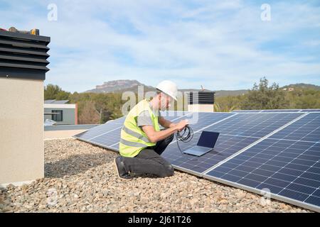 Réaliser l'installation de panneaux solaires sur le toit avec un ordinateur portable et un câble Banque D'Images