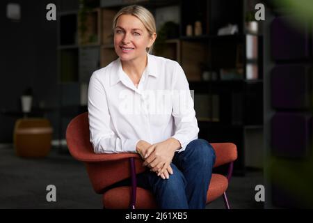 Bonne femme d'affaires avec les mains clastées assis sur la chaise Banque D'Images