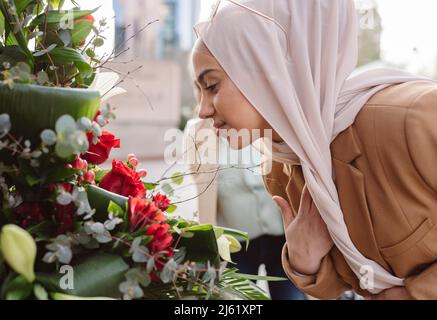 Jeune femme portant le hijab qui sent des fleurs Banque D'Images