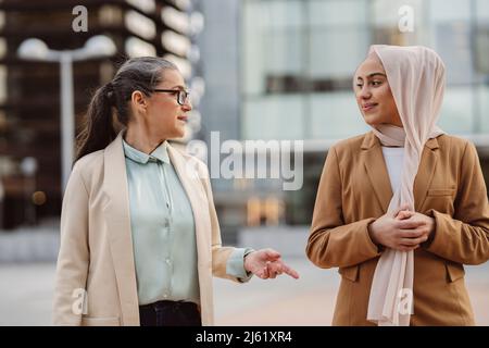 Femme d'affaires portant des lunettes discutant avec un jeune collègue Banque D'Images