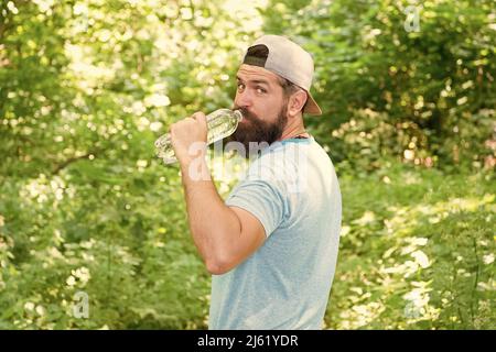 eau quotidienne. bouteille de boisson homme barbu brutale. hipster mûr avec barbe en forêt. Banque D'Images