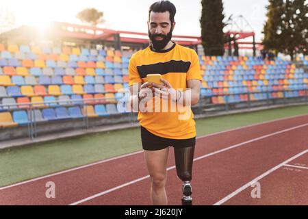 Athlète utilisant un téléphone portable debout sur la piste de course Banque D'Images