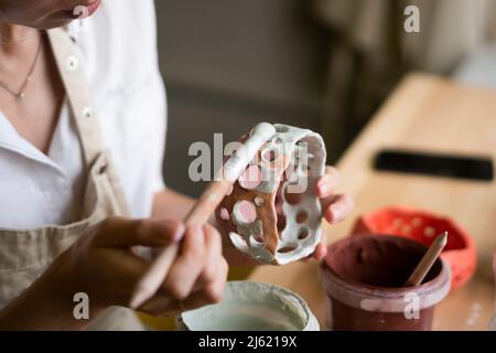 Femme peignant un bol en céramique dans un atelier Banque D'Images