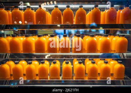 Beaucoup de jus d'orange en bouteilles sur les étagères à vendre dans un supermarché, gros plan Banque D'Images