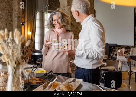 Un couple senior heureux prend son petit déjeuner buffet dans un hôtel boutique Banque D'Images