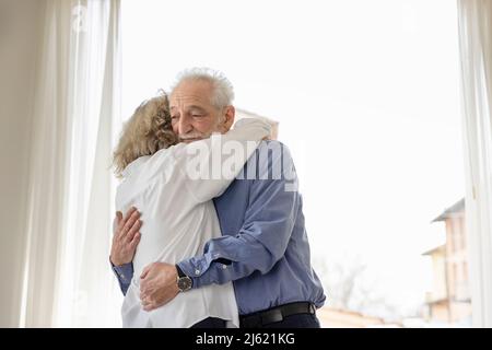 Couple senior se tenant debout près de la fenêtre à la maison Banque D'Images