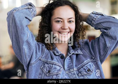 Femme souriante debout avec les mains derrière la tête Banque D'Images