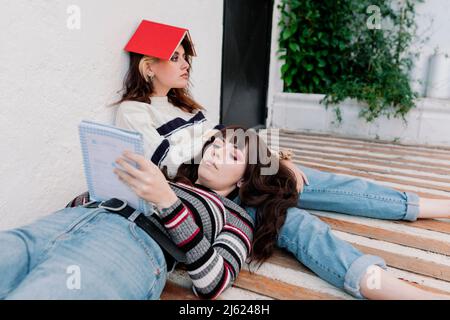 Une femme lisant un livre allongé sur un tour d'amis ennuyé Banque D'Images