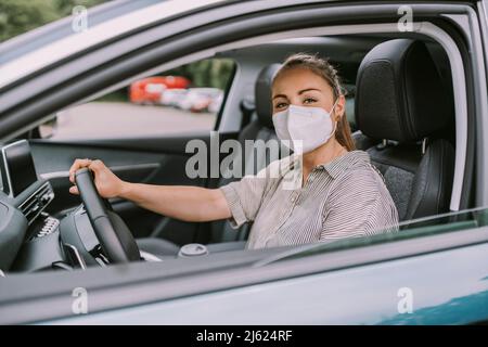 Jeune femme avec masque de protection pour la conduite de voiture Banque D'Images