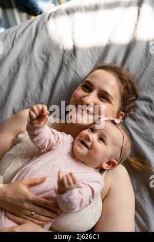 Mère heureuse avec fille couchée sur le lit ensemble à la maison Banque D'Images