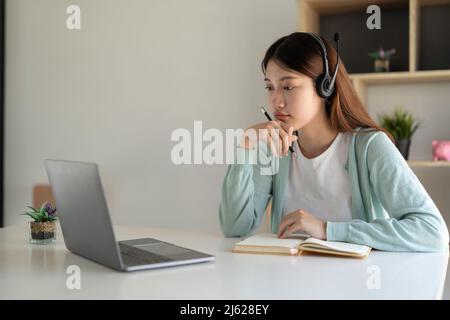 Jeune femme heureuse étudiant en ligne, regardant le webinaire, podcast sur ordinateur portable. Concept d'apprentissage en ligne Banque D'Images