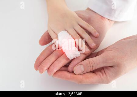 Les mains du médecin bandent le doigt douloureux avec un bandage de l'enfant.Blessure et blessure au doigt chez les enfants Banque D'Images