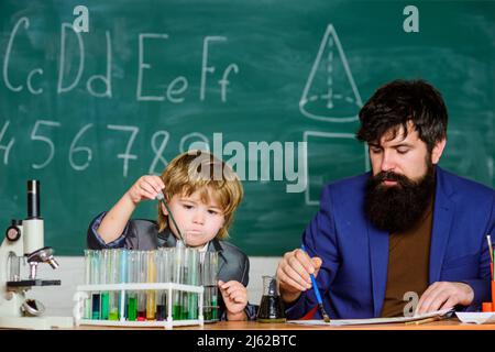 Exemple personnel inspirant. Connaissances scolaires. Journée de la connaissance vacances de septembre. Connaissances de base en chimie. Jouez avec des liquides. Enseignant et garçon Banque D'Images