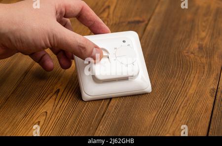 L'homme règle le thermostat électrique de température Banque D'Images