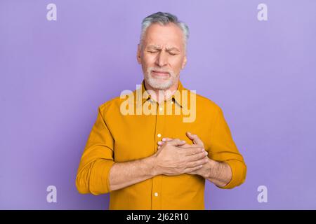 Photo de malade aîné blanc Hairdo homme mains poitrine porter chemise de moutarde isolée sur fond violet de couleur Banque D'Images