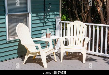 Deux chaises en plastique dans le cornor d'une nouvelle terrasse composite avec des bougies sur la maison et une petite table entre sur une maison résidentielle. Banque D'Images