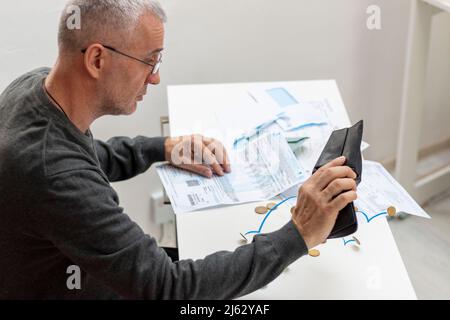 Homme mature assis à la maison, stressé et confus par calculer les dépenses de la facture ou de la facture, n'ont pas d'argent à payer, hypothèque ou prêt. Dette, faillite Banque D'Images