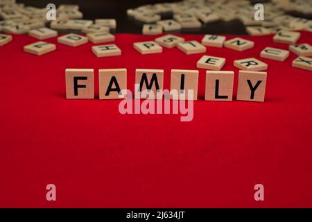 Mot 'Family' composé de plaques de bois avec des lettres sur fond de feutre rouge Banque D'Images