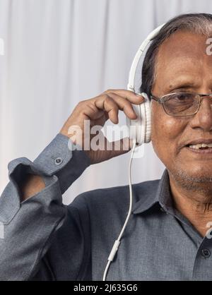 Gros plan d'un vieil Indien aime la musique avec un casque blanc Banque D'Images