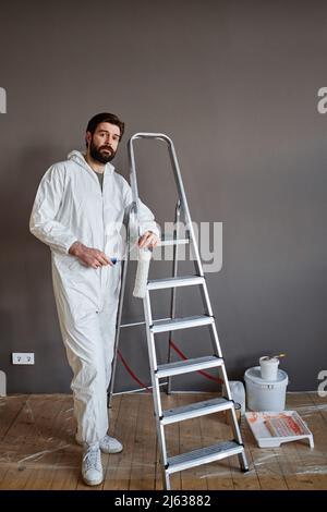 Photo verticale d'un homme caucasien portant une tenue de protection faisant des travaux de rénovation dans son appartement regardant la caméra Banque D'Images