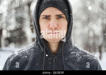 Beau sportif portant un sweat à capuche pendant son entraînement d'hiver Banque D'Images