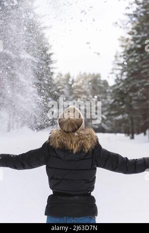 Femme jetant de la neige dans l'air pendant la journée froide d'hiver Banque D'Images