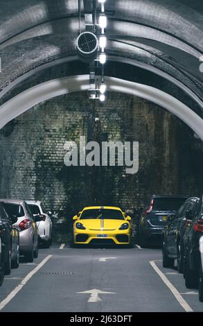 Un parking souterrain ou un parking dans une ville faisant bon usage de l'espace limité avec une voiture jaune vif proéminent Banque D'Images