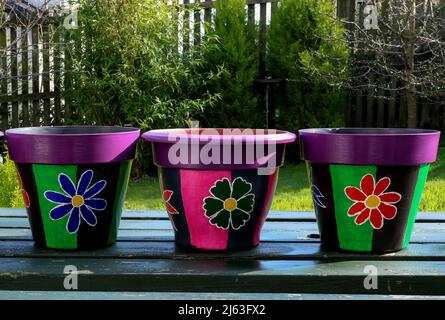 Pots de plantes peints à la main sur une table de pique-nique de jardin Banque D'Images