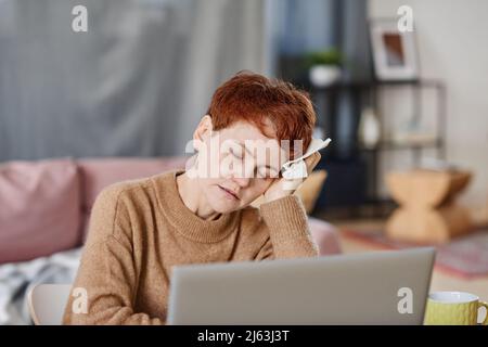 Tir de gros plan horizontal moyen d'une femme caucasienne mature souffrant de fièvre et de maux de tête plus graves se reposant tête sur la main Banque D'Images