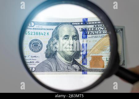 Loupe - 100 dollars US. Concept sur le thème de la vérification de l'authenticité de l'argent Banque D'Images