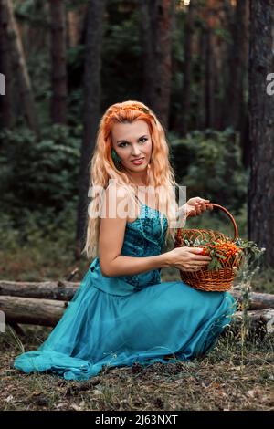 Une jeune femme enroulée dans les bois tient un panier de baies dans ses mains Banque D'Images