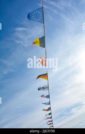 Les drapeaux de plusieurs pays pendent d'une corde, contre beaucoup de ciel bleu Banque D'Images