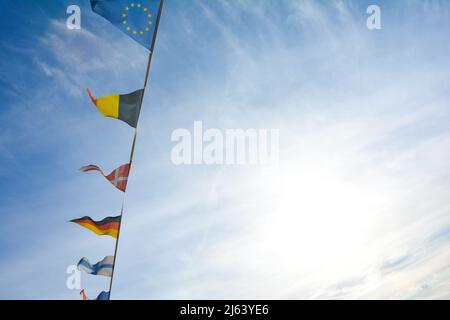 Les drapeaux de plusieurs pays pendent d'une corde, contre beaucoup de ciel bleu Banque D'Images