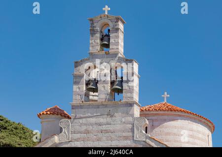 Clocher de l'église avec croix sur le dessus et trois grandes cloches extérieures en métal contre un ciel bleu avec des rooves rondes en terre cuite Banque D'Images