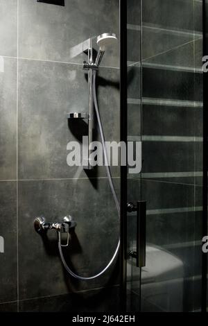 Douche de luxe minimaliste, entièrement décorée avec des carreaux gris foncé, avec une pomme de pluie Banque D'Images