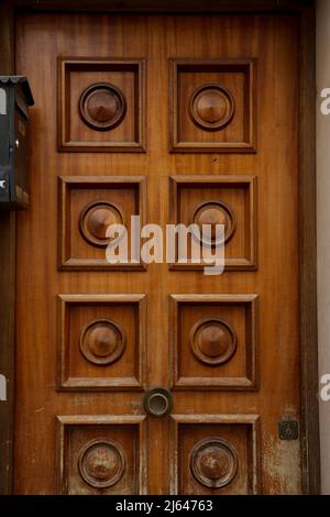 Porte en bois avec détails géométriques à côté de la boîte aux lettres en métal noir Banque D'Images