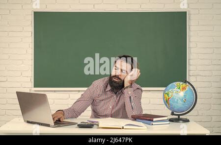 homme endormi. éducation formelle. journée du savoir. professeur barbu à la leçon. homme brutal travaille en classe avec un tableau noir. préparez-vous à l'examen Banque D'Images