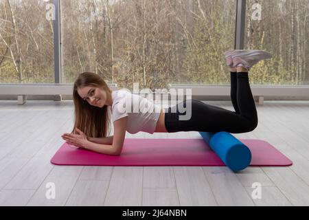 Sur le rouleau de forme physique mfr fille est rouge tapis fenêtre caucasien, pour la classe à la maison pour l'activité de l'entraînement de style de vie, étirement. Copie de planche Banque D'Images