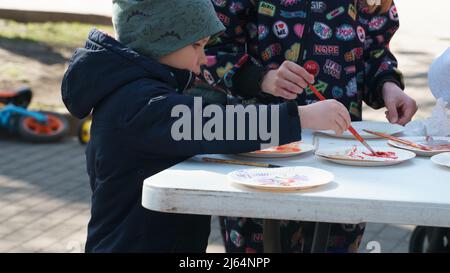 Olaine, Lettonie - 18 avril 2022. Enfants peindre avec des couleurs. Atelier de création de couleurs en plein air pour les familles avec enfants au printemps, le tim de Pâques festif Banque D'Images