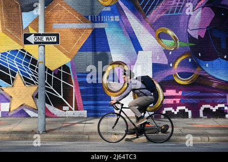 Un de ses usagers passe son vélo devant une fresque sur Wilmington Street, dans le centre-ville de Raleigh, en Caroline du Nord. Banque D'Images