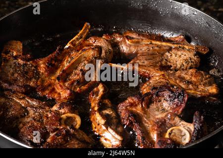 Cuisson des côtelettes d'agneau dans une poêle. Cuisson sur une cuisinière à gaz. Banque D'Images