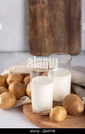 Lait à base de légumes dans deux verres transparents.Lait de pomme de terre de remplacement et tubercules de pomme de terre sur table grise Banque D'Images