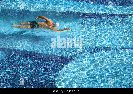 Vue aérienne d'un homme qui nage dans une piscine par beau temps. Banque D'Images