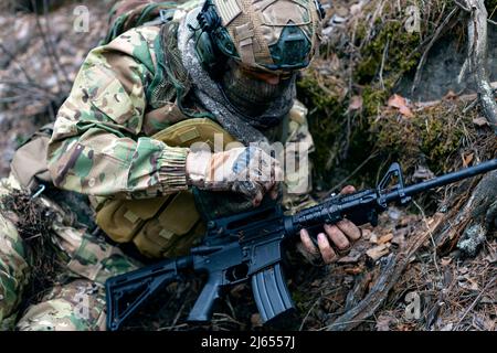 Le soldat mercenaire durant le conflit nettoie l'arme de la terre et de la saleté. Il se prépare à attaquer l'ennemi. Vue rapprochée. Mise au point sélective. Banque D'Images