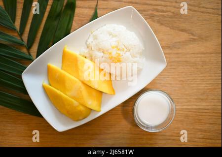 Vue de dessus, mangue mûre douce avec riz collant et lait de coco spécial sur une table en bois. Desserts thaïlandais Banque D'Images