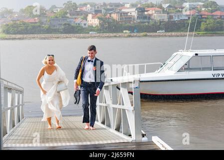 Tout juste marié, Amy et Kieran font leur chemin pieds nus et sous la pluie, en haut d'une rampe de bateau d'une promenade en bateau-taxi sur le port de Sydney à leur réception Banque D'Images