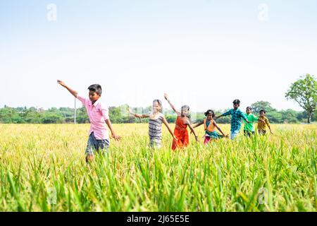 Groupe heureux de jeunes filles de village jouant au milieu du paddy champ en équilibrant - concept de bonheur, de détente, de liberté et insouciant Banque D'Images