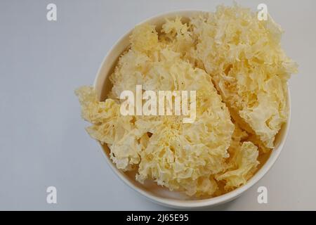 Neige desséchée ou champignon blanc, Tremella fuciformis, dans un bol, isolé sur blanc Banque D'Images