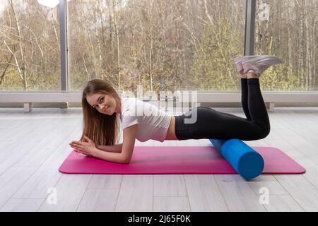 Girl fitness le tapis repose sur le rouleau mfr le tapis rouge fenêtre sportswear, de l'exercice à l'intérieur pour l'activité pour l'entraînement de style de vie, la motivation d'étirement Banque D'Images